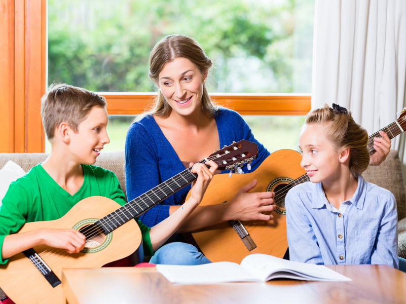 Cairns Paediatric Psychology - Example to children Family making music at home with guitar, mother, daughter and son playing