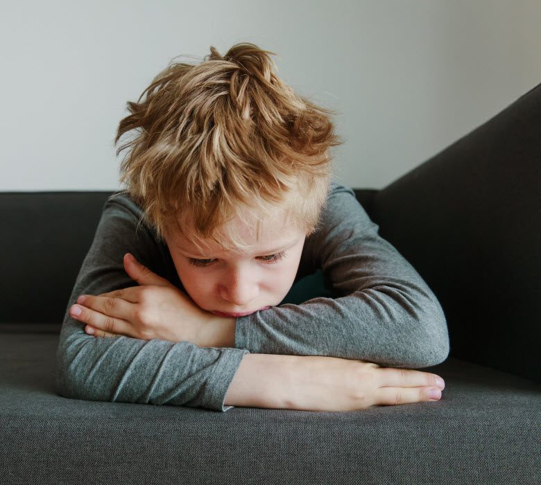 Cairns Paediatric Psychology - Emotional Reactions to Grief Sad child leaning on a sofa