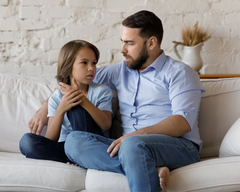 Cairns Paediatric Psychology - Name and talk about feelings Father and son seriously talking while sitting on the couch