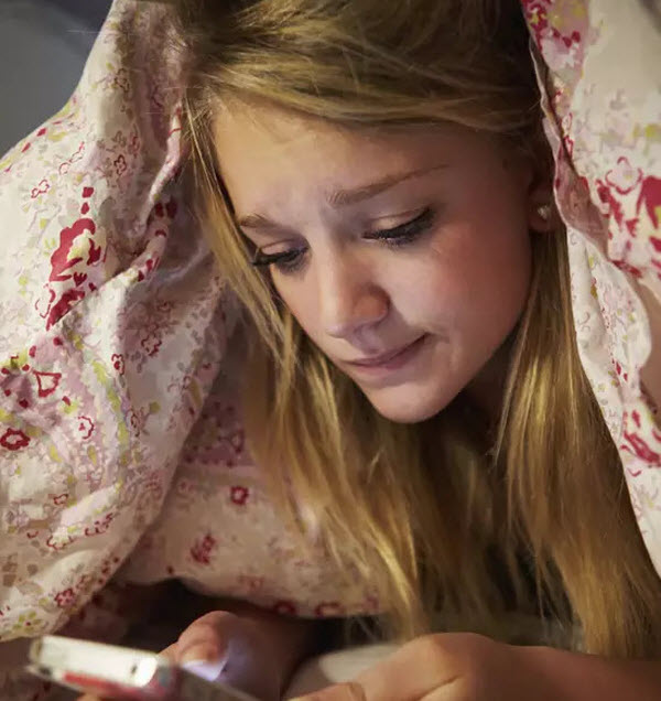 Cairns Paediatric Psychology - Organisations Sad young lady using mobile phone while on the bed under the blanket