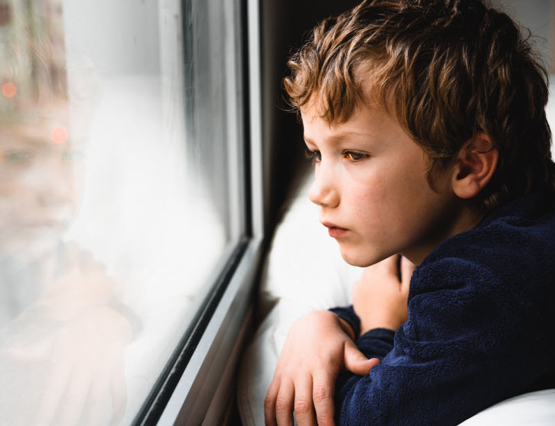 Cairns Paediatric Psychology - Saying goodbye to a child Young boy unhappily looking at outside of a window